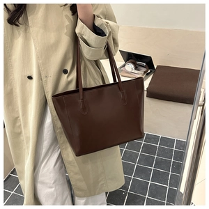 Detail of a large dark brown tote bag with smooth finish and fine stitching on the handle