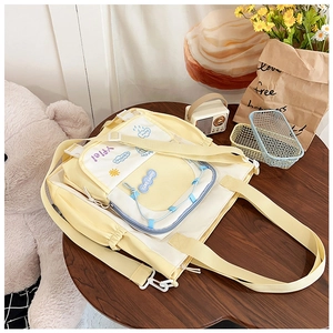 Détail d'un sac à dos en toile jaune et blanc avec broderie sur une table en bois brun