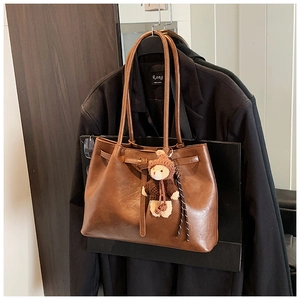 Nahaufnahme der braunen Vintage-Leder-Tote mit Bärenanhänger und Schulterriemen