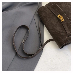 Detailed view of espresso brown leather briefcase bag with golden twist lock and textured finish
