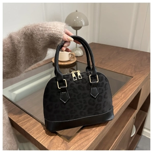 Gros plan du sac coquillage noir à motif léopard avec zip doré et base en cuir lisse noir