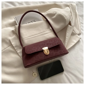 Detail of burgundy leopard print handbag with gold vintage clasp on a cream blazer