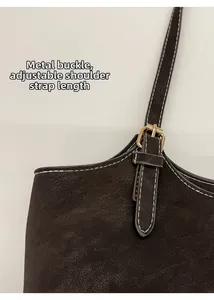 Détail du sac marron vintage avec surpiqûres blanches et boucle dorée réglable