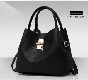 Detail of midnight black pebbled leather bucket bag with gold lock and chain hardware