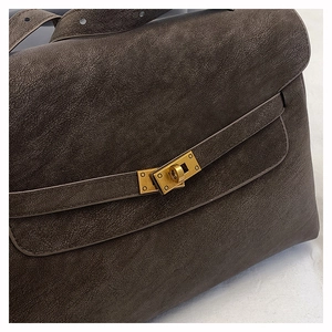 Macro shot of the vintage gold twist lock and textured dark brown leather on tote bag