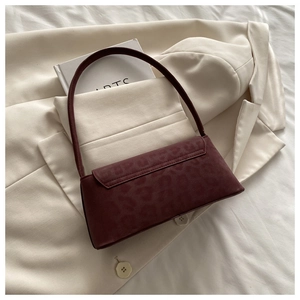Close-up of deep burgundy baguette bag featuring subtle leopard print and matte texture