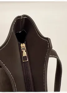 Détail de la fermeture éclair dorée et des coutures précises sur le sac cabas marron foncé