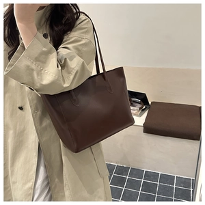 Borsa tote in pelle marrone mostrata con un elegante trench coat beige