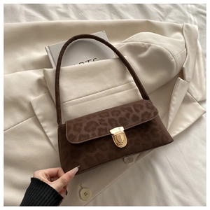 Detail of leopard print suede underarm bag with gold metal clasp on beige blazer