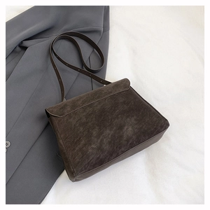 Detailed view of dark brown matte suede shoulder bag with adjustable strap and flap