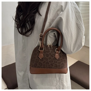 Vue détaillée du sac coquille à motif léopard avec zips dorés et bandoulière en cuir