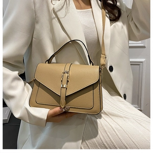 Close-up of khaki pebbled leather texture and golden horseshoe buckle on stylish crossbody bag