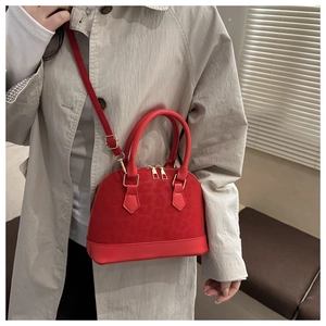 Detailed view of red leopard-embossed dome bag with gold hardware worn as crossbody