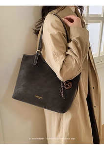 Detail of minimalist black tote bag featuring gold lettering and retro pendant charm