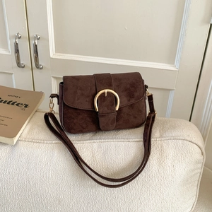 Retro dark brown crossbody bag with gold U-shaped buckle on a minimalist cream sofa
