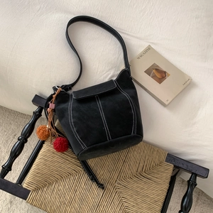 Retro black suede bucket bag with white stitching and colorful tassel charm