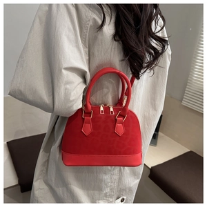 Détail d'un sac dôme rouge vif avec texture léopard et fermetures éclair dorées chic