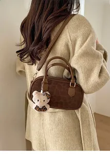 Dettaglio borsa a bauletto leopardata con ciondolo di peluche su cappotto beige