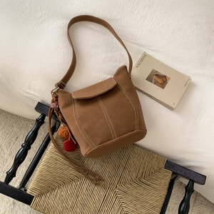 Vintage brown suede bucket bag with contrast stitching and boho pom-pom charm decoration