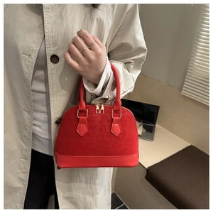 Détail du sac à main rouge en forme de coquille avec texture léopard et base en cuir lisse