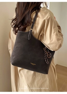 Close-up of dark brown tote bag with contrast stitching and metallic buckle details