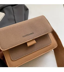 Detail of brown contrast leather crossbody bag with wide woven strap and matte texture