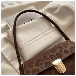 Detail of dark brown leopard jacquard shoulder bag with golden metal buckle and suede finish