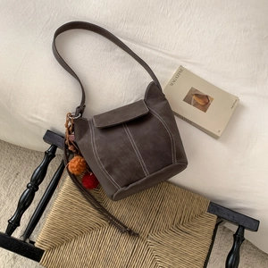 Brown vintage faux suede bucket bag with white contrast stitching and colorful pompom charms