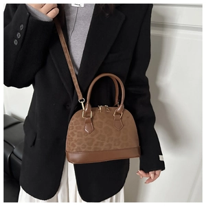 Gros plan d'un sac coquillage léopard avec anses brunes sur une tenue avec blazer