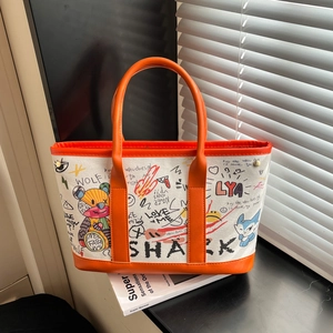 Sac seau en toile graffiti avec bordure en cuir orange sur un rebord de fenêtre