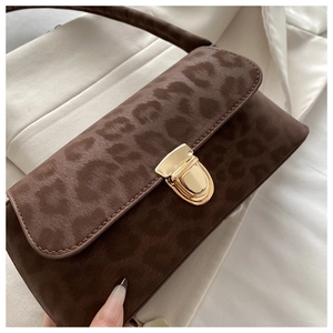 Macro detail of dark brown leopard print suede handbag with elegant golden metal lock