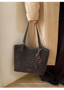 Detail of matte leather texture and gold embossed logo on a dark brown tote bag