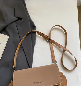 Detail of light brown leather crossbody bag with adjustable strap and front lettering