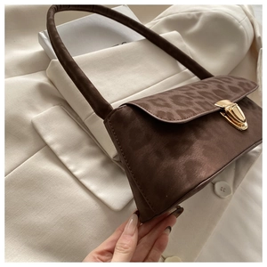 Close-up of leopard print shoulder bag with golden vintage clasp and glossy texture
