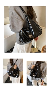 Detail of glossy black hobo bag with metal logo and plush bear charm on side