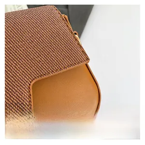 Detail of a brown crossbody bag featuring woven fabric and smooth leather patchwork