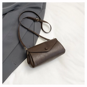 Detail of retro dark brown leather crossbody bag with envelope flap on grey suit background