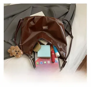 Detail showing high capacity of dark brown tote bag with plush bear charm and tablet