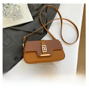 Detail of a brown textured crossbody bag featuring a golden geometric buckle and leather flap