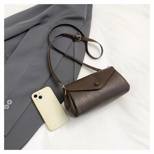 Detail of dark brown faux leather texture and magnetic snap on minimalist flap bag