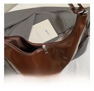 Top view detail of dark brown glossy leather half-moon bag with silver zipper closure