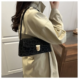 Detail of a chic leopard print underarm bag with gold lock worn with a beige trench coat