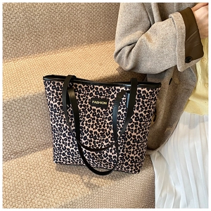 Macro shot of fashion leopard print tote bag with black strap and brand tag detail