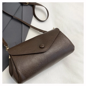 Detailed view of dark brown crossbody bag with litchi texture and gold metal clasp