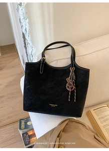 Détail du cabas en daim noir avec surpiqûres blanches et pendentif boulier vintage