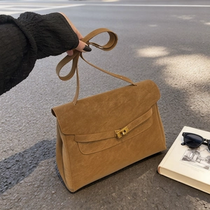 Brown suede tote bag with golden twist lock and adjustable strap in street style view