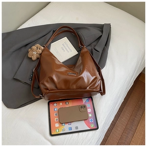 Brown vintage hobo tote bag detail with metal logo and cute plush bear charm decoration