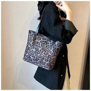 Detail of leopard print tote bag with black leather straps and gold FASHION label