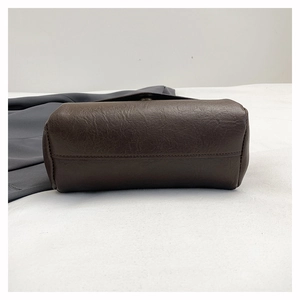 Close-up of dark brown leather handbag with pebble grain texture and stitching details