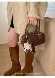 Borsa Boston in pelle marrone con ciondolo peluche, cardigan beige e stivali di camoscio